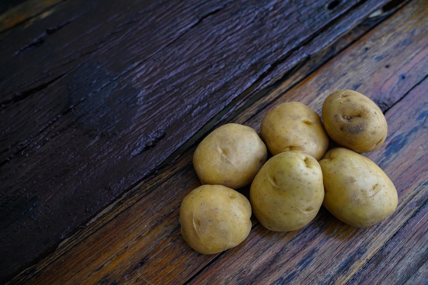 Raw potato diet.  Fresh potatoes on wooden floor . Space for messages . Raw potatoes that can be used in many dishes. photo