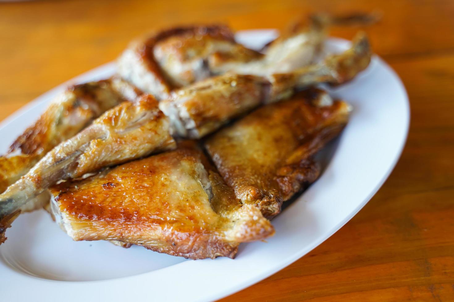 Grilled chicken in white plate on wooden floor - traditional Thai menu  It's a simple and popular dish. photo