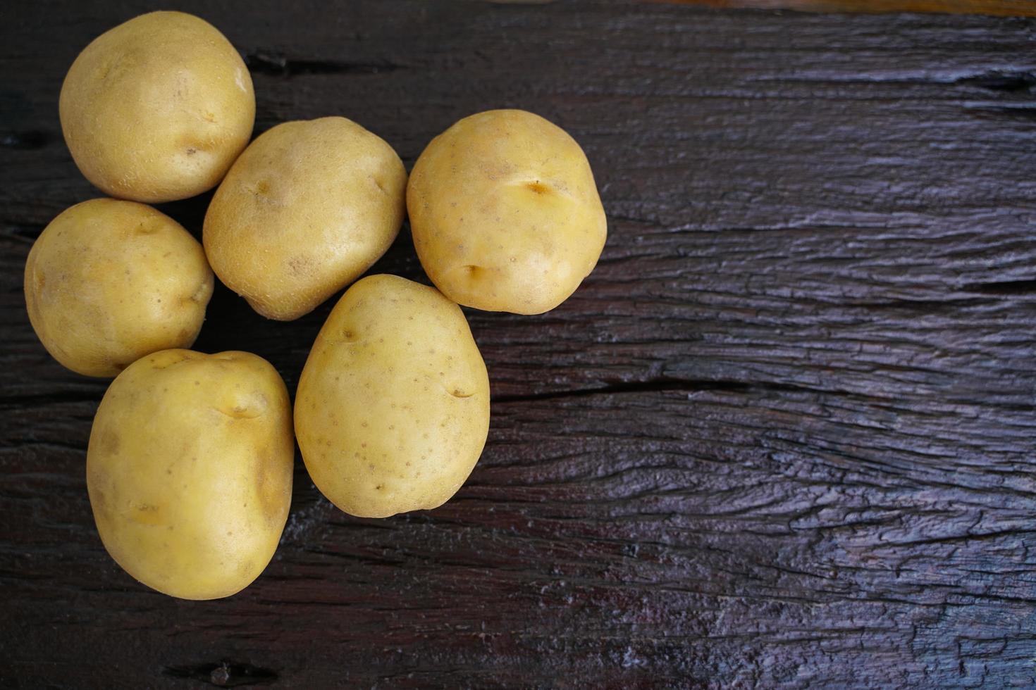 Dieta de papa cruda. papas frescas en el piso de madera. espacio para mensajes. patatas crudas que se pueden utilizar en muchos platos. foto