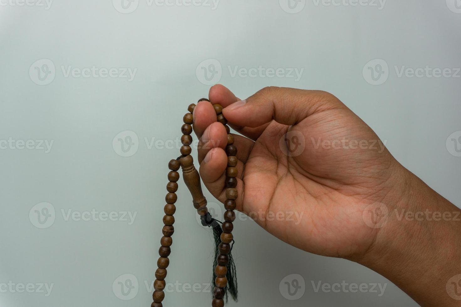 hand holding wooden tasbih beads isolated. islamic prayer beads. moslem praying concept photo