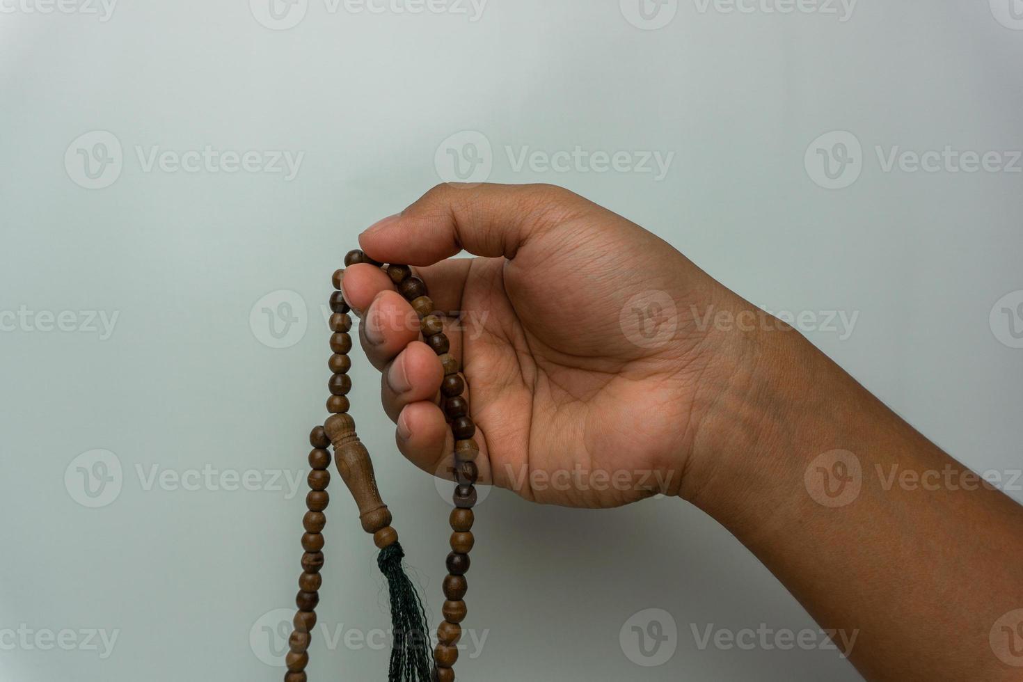 mano sosteniendo cuentas de tasbih de madera aisladas. cuentas de oración islámicas. concepto de oración musulmana foto