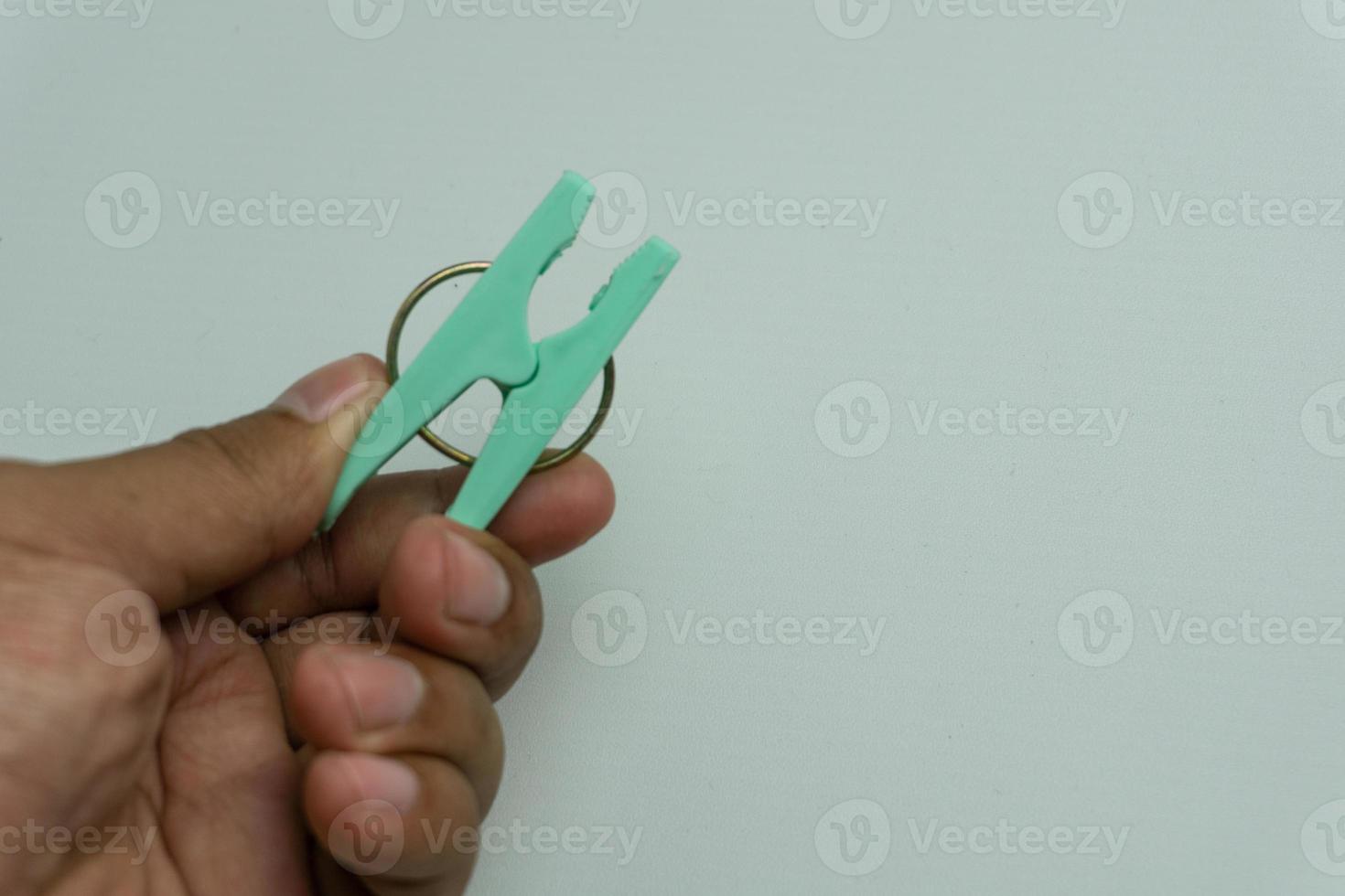 hand holding green clothes peg or clothes pin isolated on white backround photo