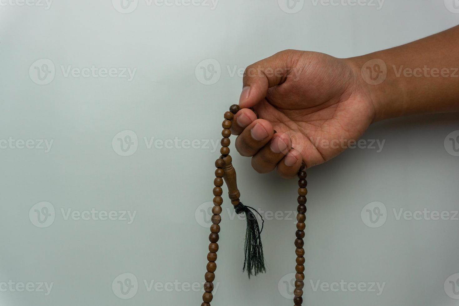hand holding wooden tasbih beads isolated. islamic prayer beads. moslem praying concept photo