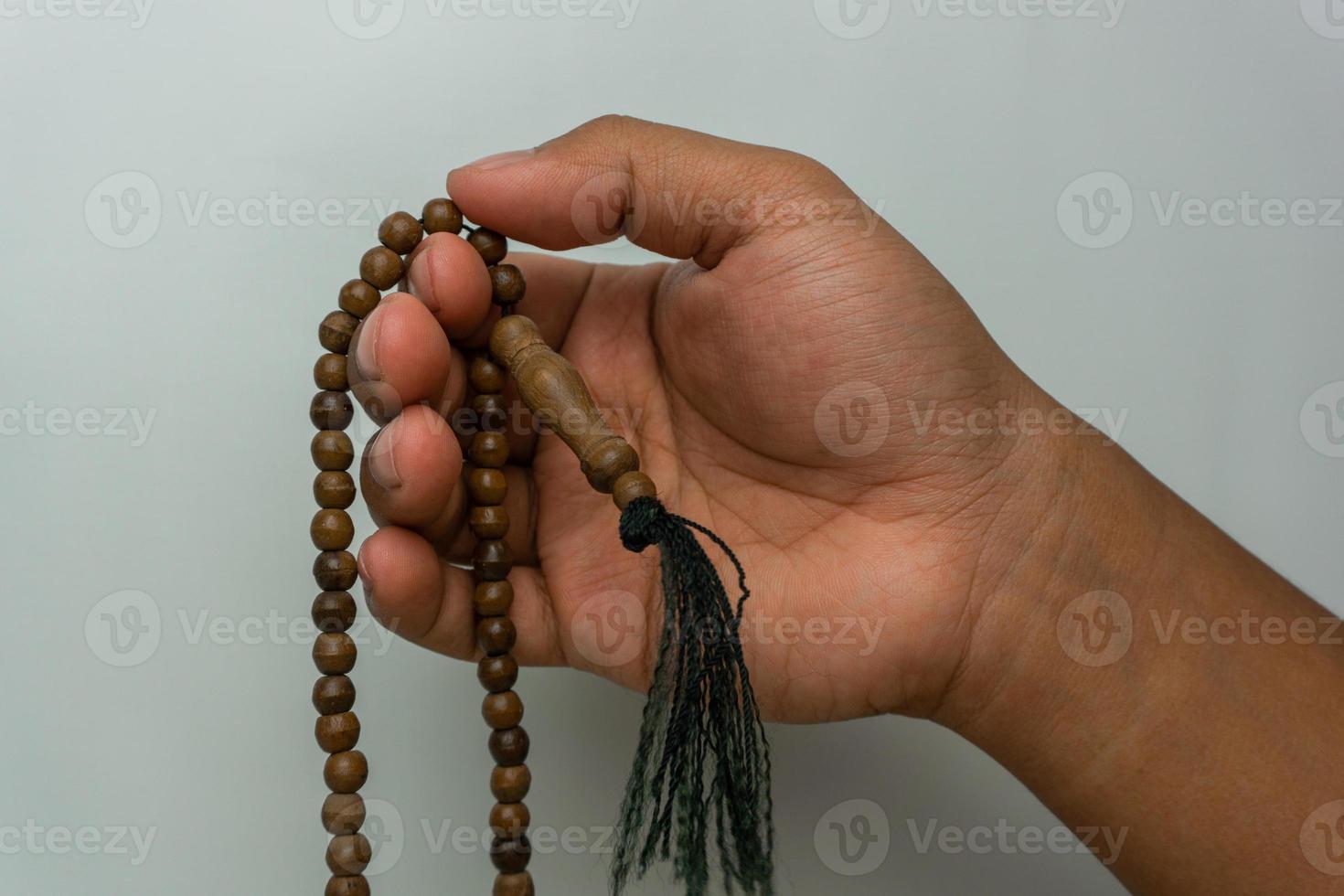 hand holding wooden tasbih beads isolated. islamic prayer beads. moslem praying concept photo