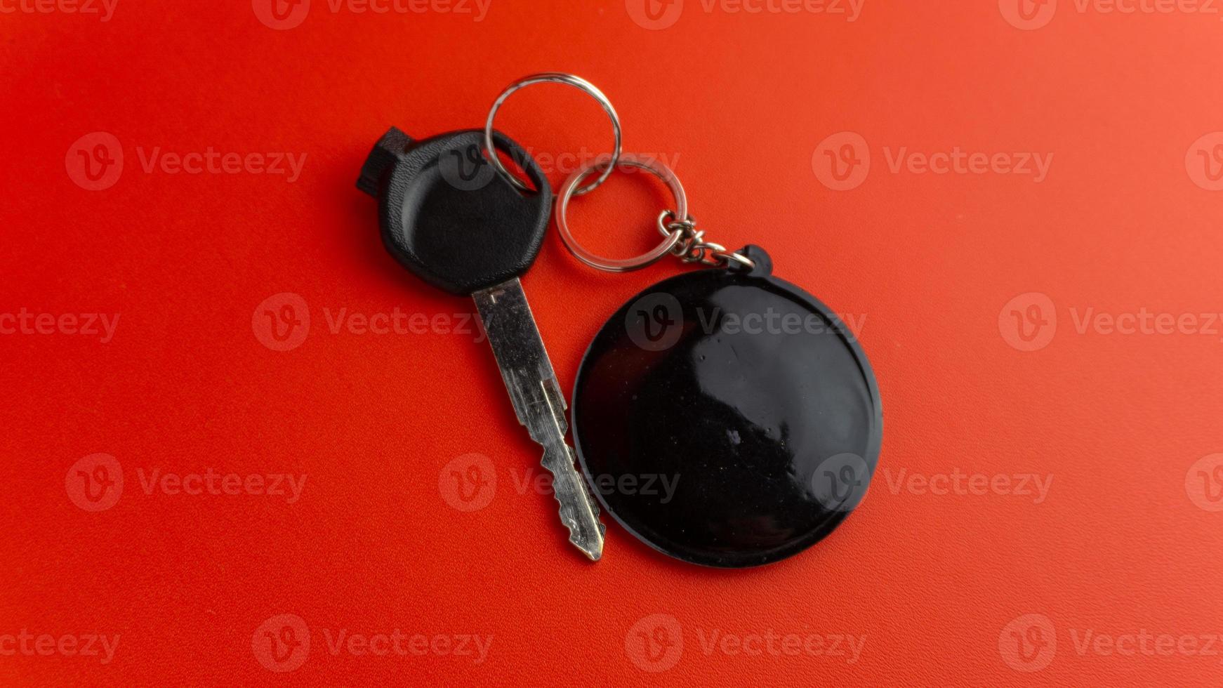 Black motorcycle key with black round keychain on red background. keychain mockup for design photo
