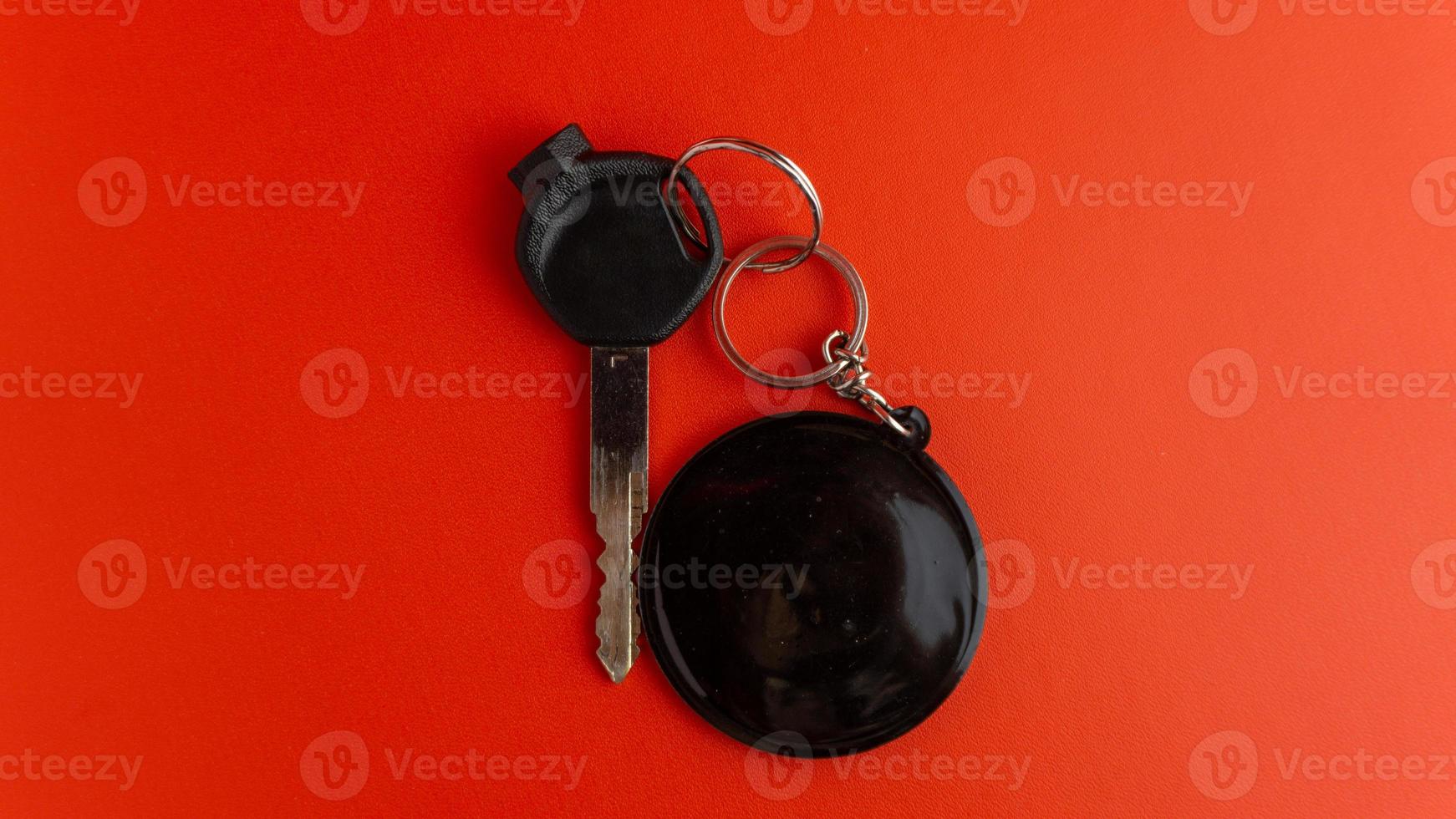 Black motorcycle key with black round keychain on red background. keychain mockup for design photo