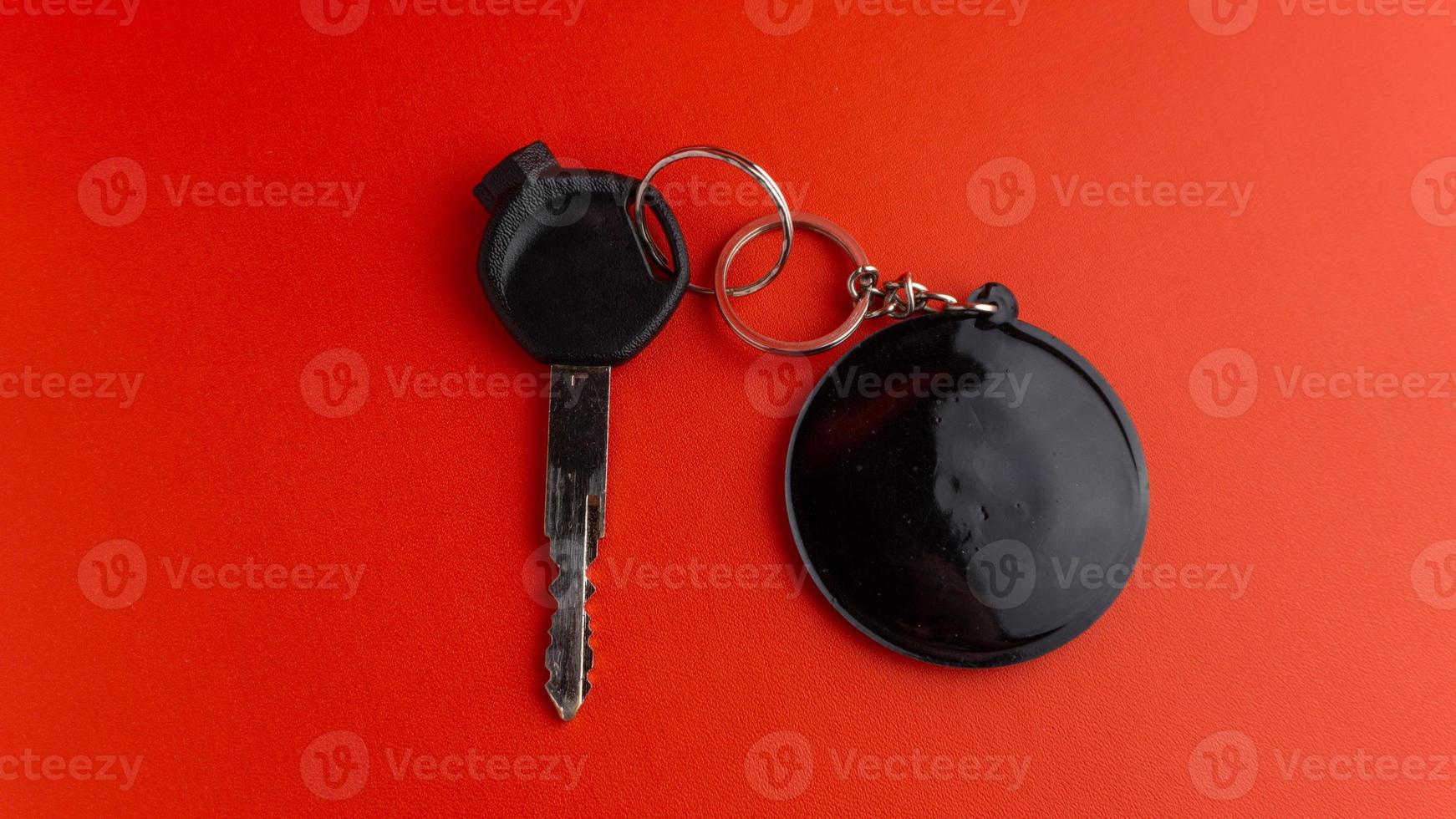 Black motorcycle key with black round keychain on red background. keychain mockup for design photo