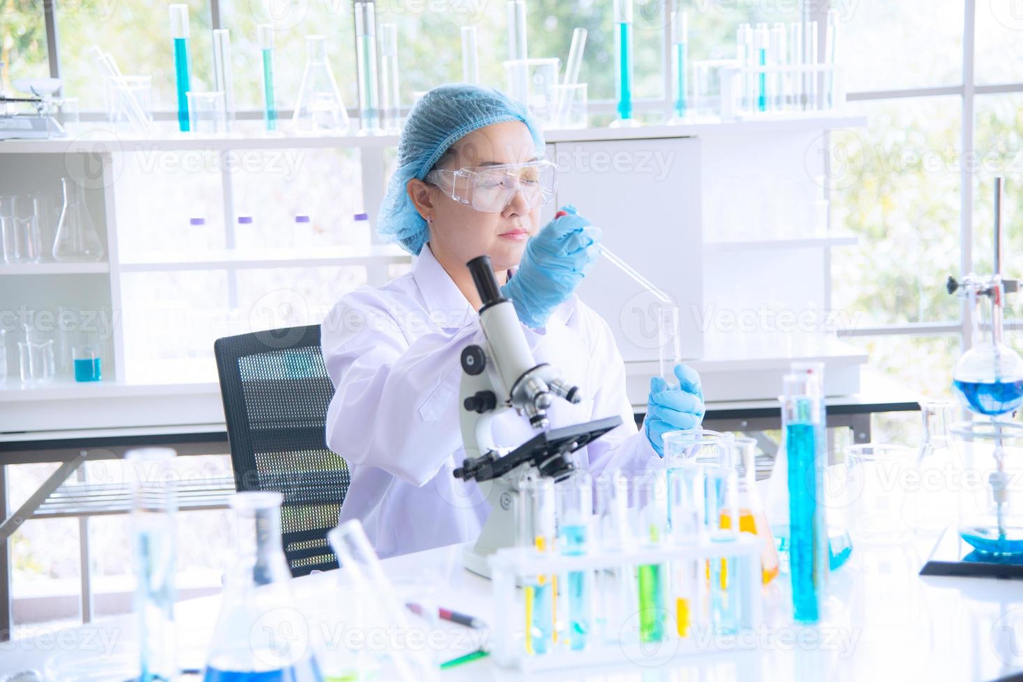 Asian woman scientist, researcher, technician, or student conducted research or experiment by using microscope which is scientific equipment in medical, chemistry or  biology laboratory photo