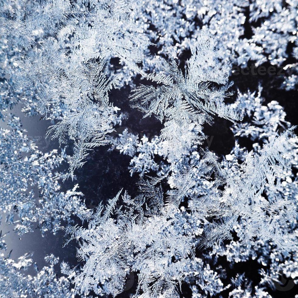 copos de nieve y patrón de escarcha en el vidrio de cerca foto