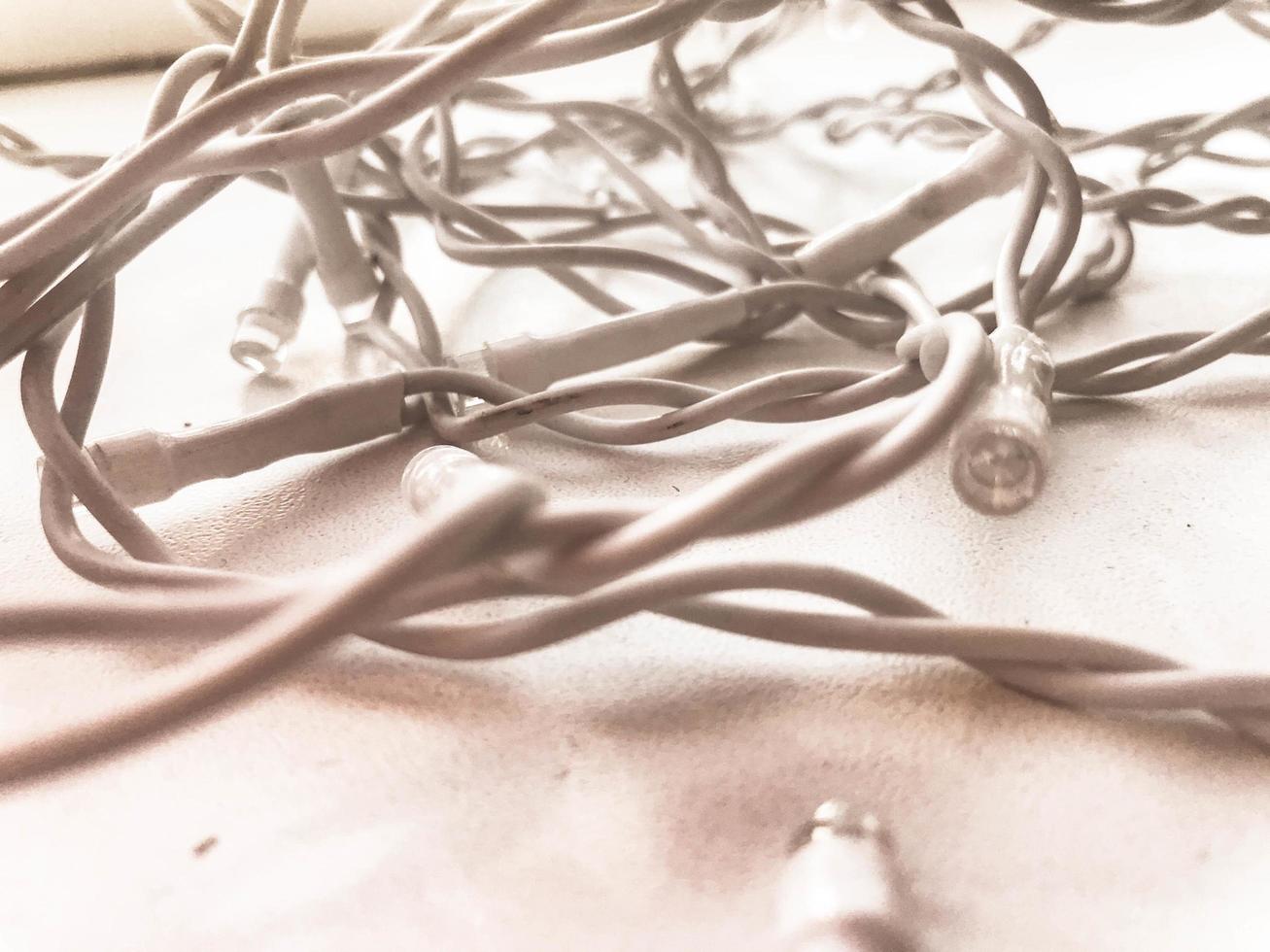 Twisted white wires of a garland in white rubber insulation with light bulbs on a white background photo