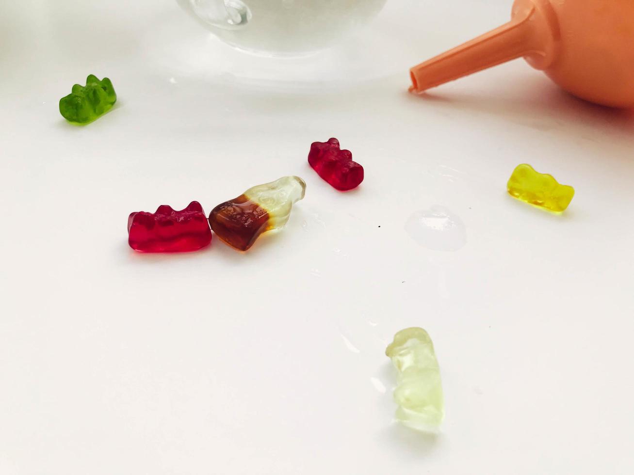 gummy gelatinous bears lie on a wet white matte background. sweet candies are next to the watering can. delicious high-calorie dessert. candy scattered on the table photo