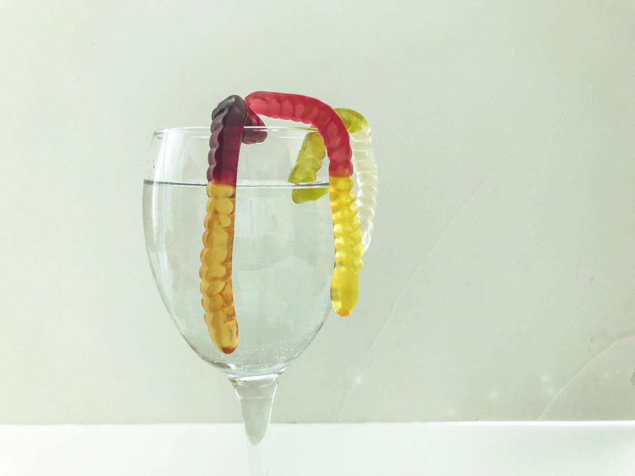 Bright tasty beautiful juicy multi-colored gelatinous gummy sweet candies worms lie in a transparent glass wine glass. Sweet dessert cocktail photo