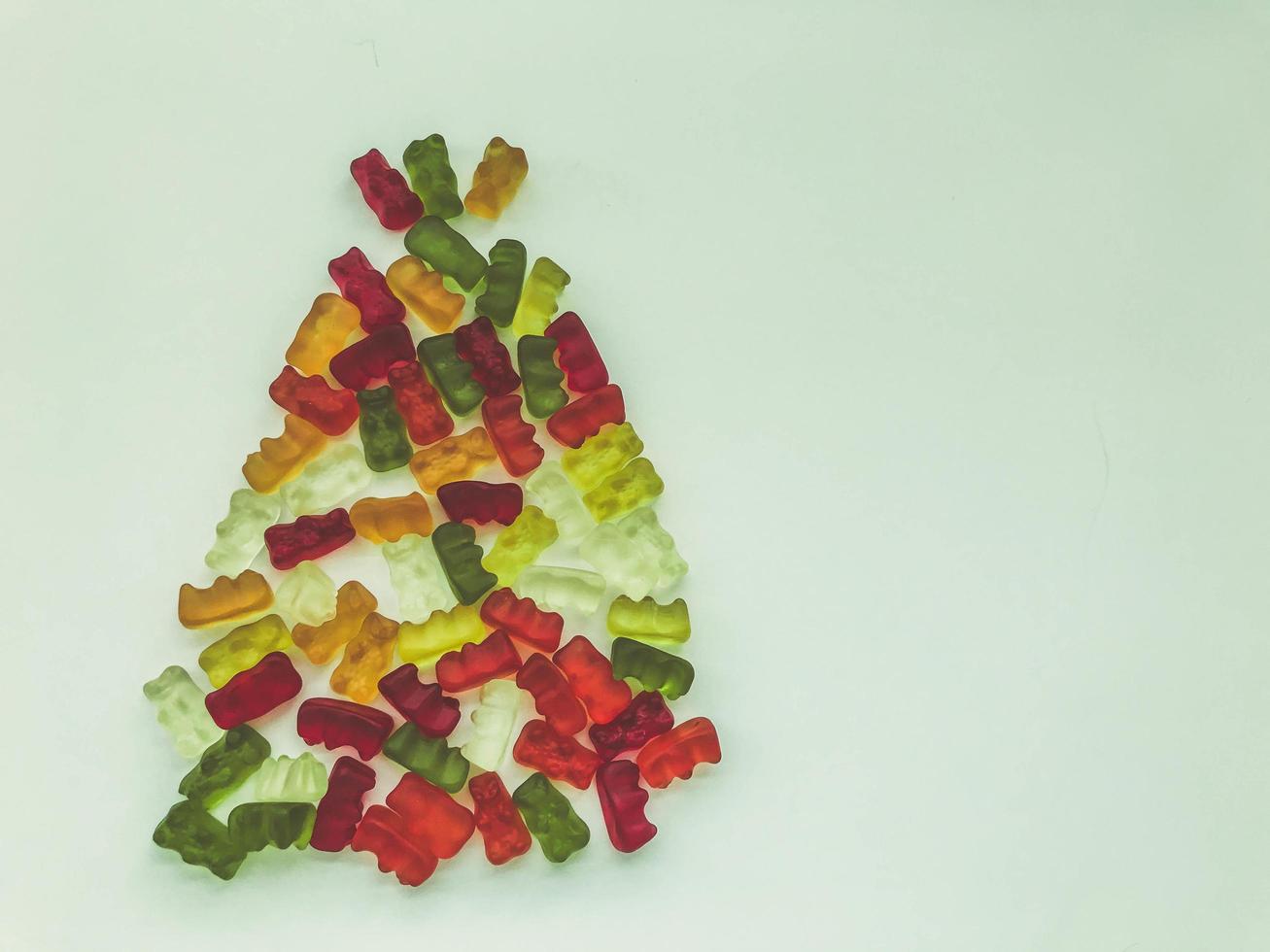 árbol de navidad hecho de deliciosas y dulces gomitas. mermelada en forma de osos, botellas de limonada. árbol de navidad hecho de caramelos brillantes, coloridos y dulces foto