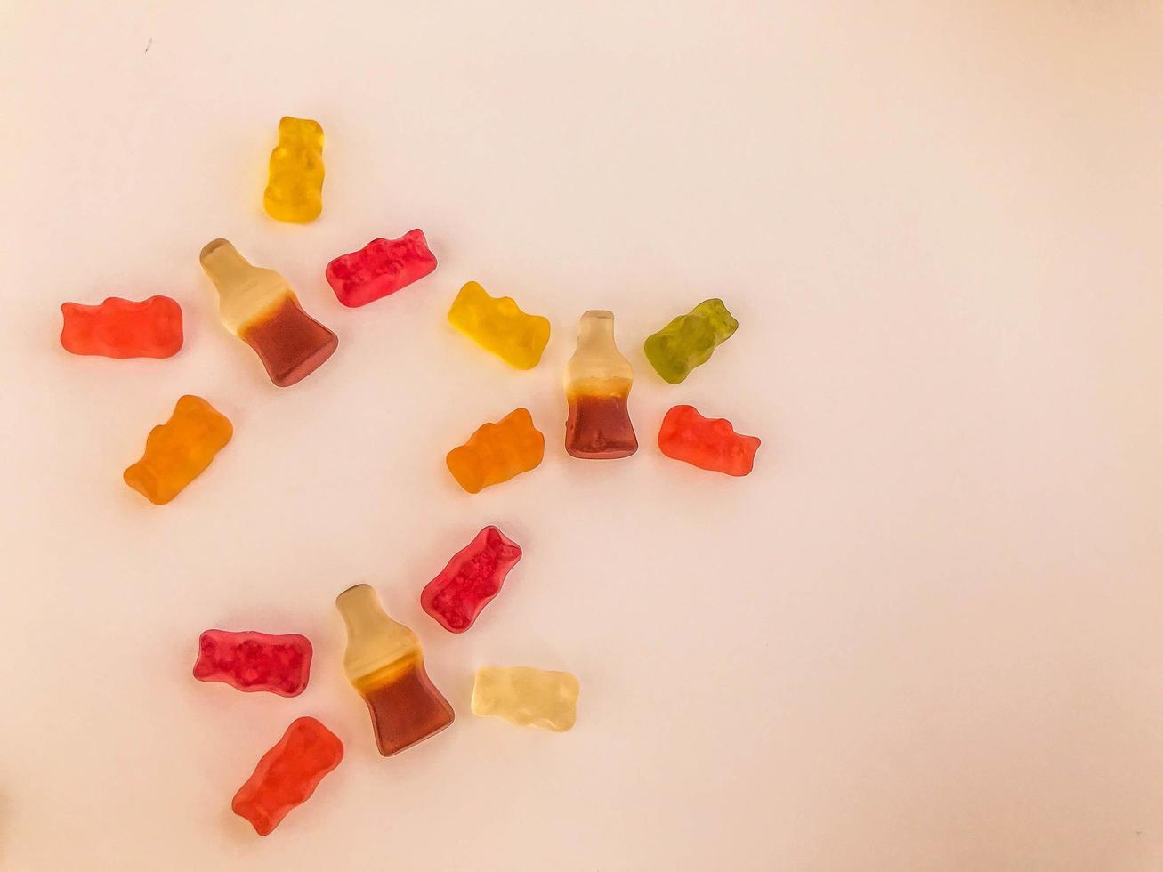 gummy candies on a pink matte background. marmalade is laid out in the form of butterflies. gummy bears and lemonade bottles. delicious candies in the shape of flying animals photo