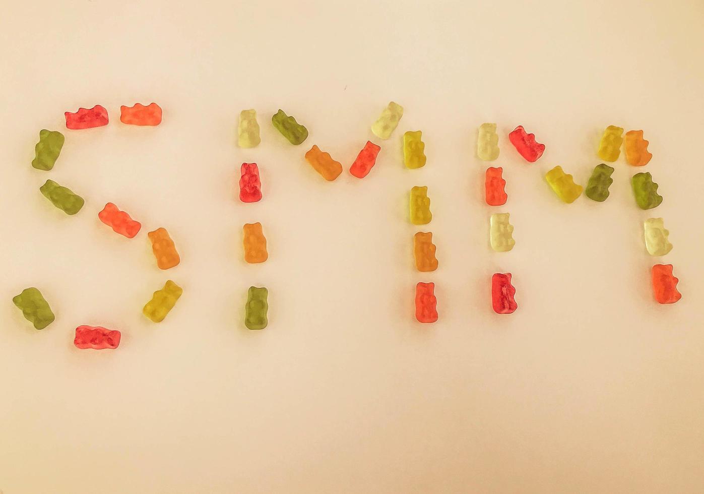 letter from multi-colored gummy bears. Letter S and M made from gelatinous candies on a matte orange background. edible word SMM. marketing of gummies. bright sweet gummy bears photo