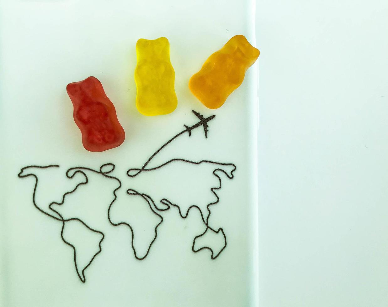 gummy bears are going to travel the world. bears fly on vacation and examine the map. the journey of the gelatinous bears to the other end of the planet. bright journey, food games photo