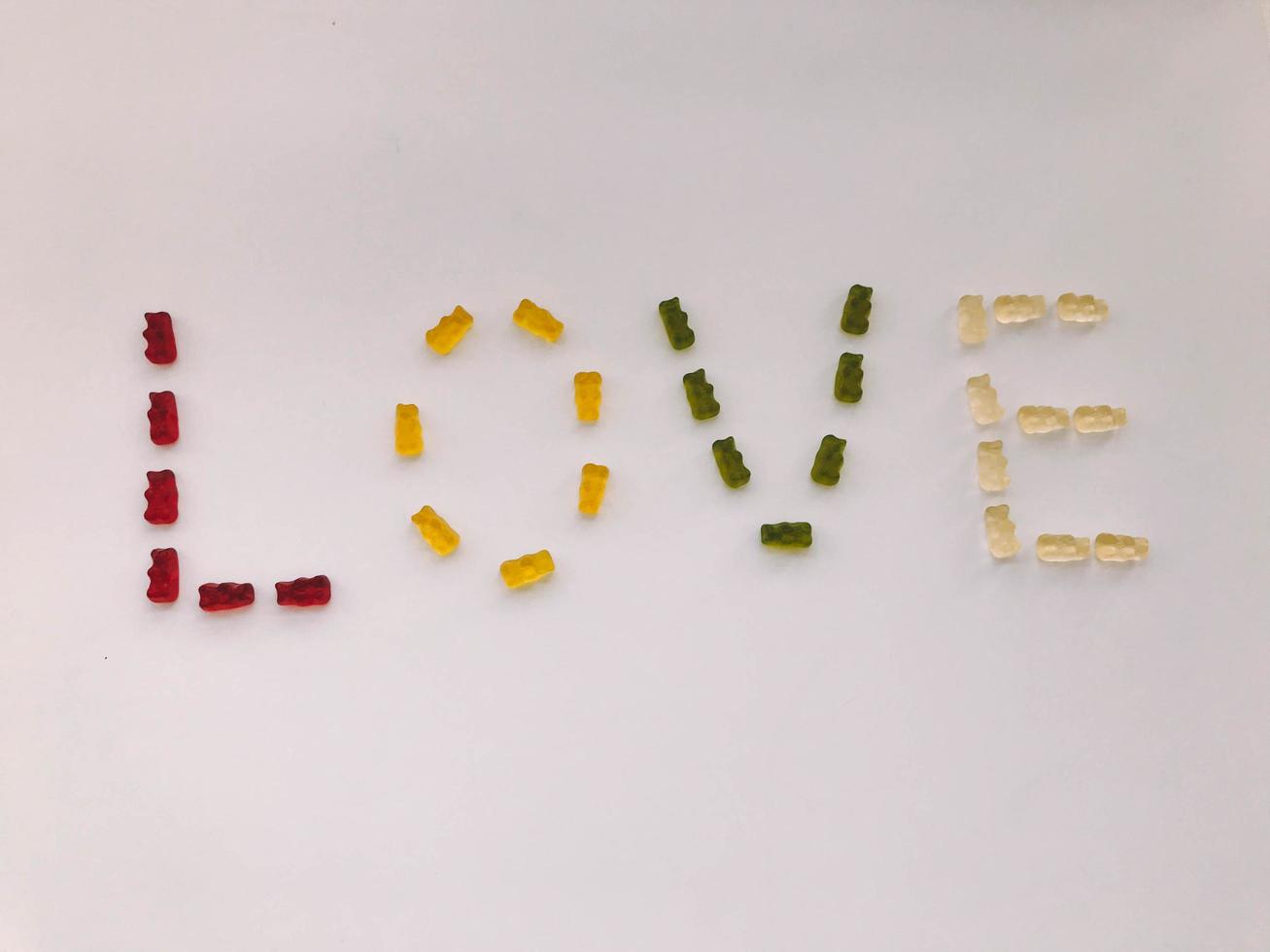 word love made from marmalade. letters from gummy bears in green, white, yellow and green colors. high-calorie delicious dessert. creative lettering with edible letters photo