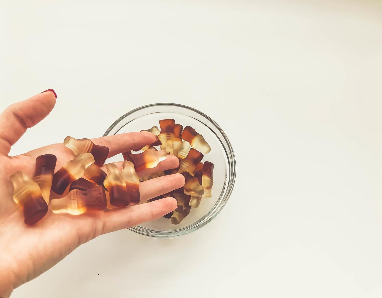 jelly in the form of a bottle is poured from the hand into a round plate. dessert for children and adults. delicious juicy gummy gummies. fruit gelatinous sweets photo