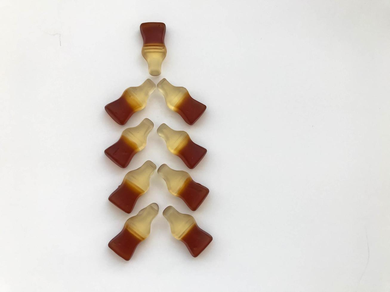 Christmas tree made from gummy bottles with lemonade on a white matte background. delicious and high-calorie dessert. fragrant gelatinous candies in the shape of a Christmas tree. Christmas Eve photo