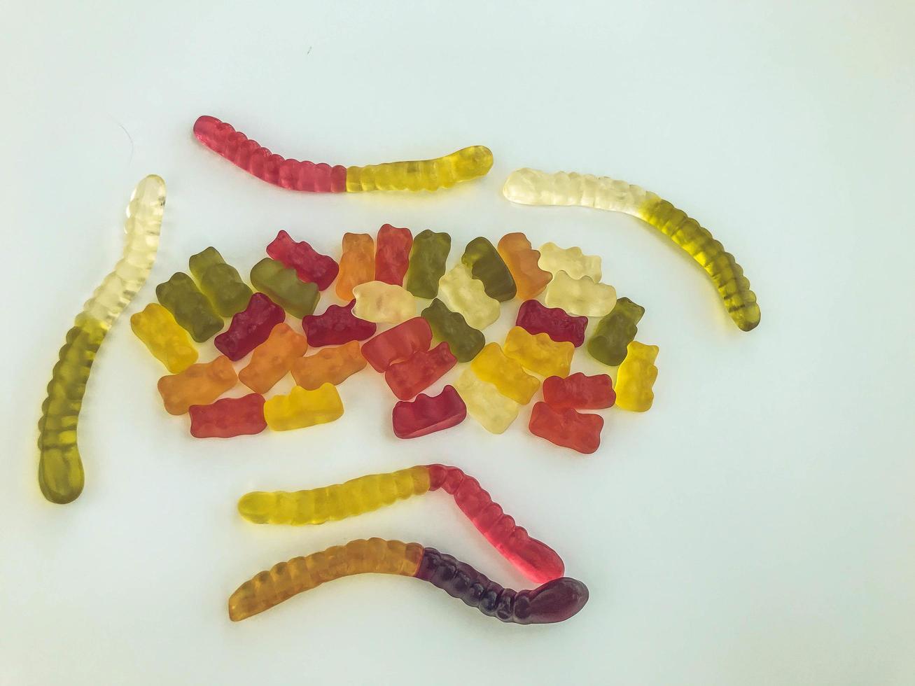 gummy candies lie on a white matte background. gelatinous worms and bears of different colors intertwined with each other. mouth-watering culinary masterpieces. decorating cakes and pastries photo