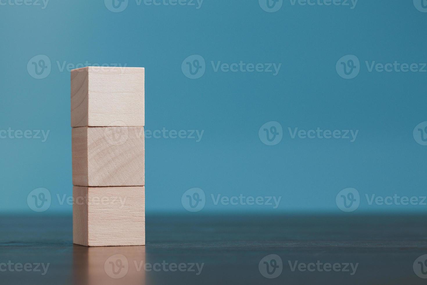 Stacking blank wooden cubes on blue background with copy space for input wording and infographic icon. Empty brown wooden object block for symbol icon put technology, zero gravity, business concept. photo