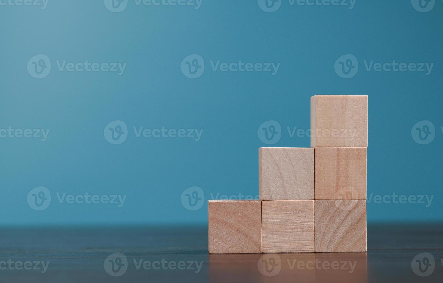 Stacking blank wooden cubes on blue background with copy space for input wording and infographic icon. Empty brown wooden object block for symbol icon put technology, zero gravity, business concept. photo