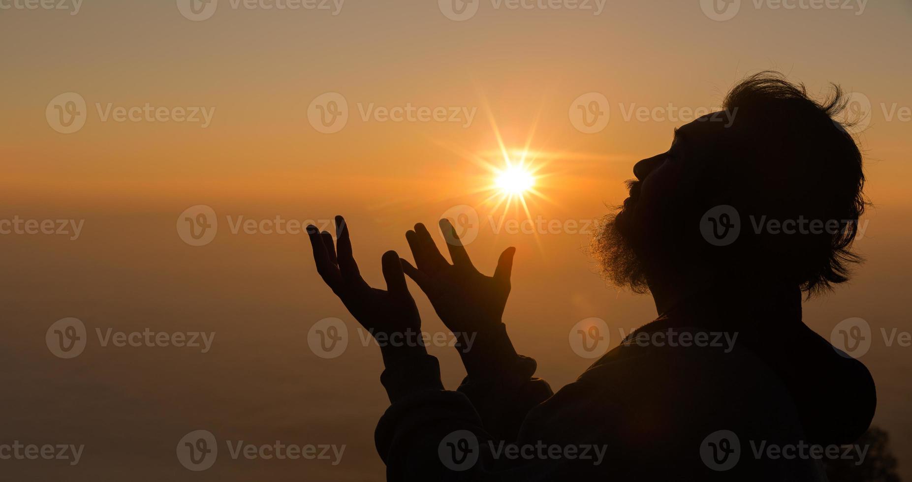 Concept Christian person worship or pray to God. Christian man silhouette with love, faith, devotion to God with sunrise sky background.Male worship God for peace, victory, success with hope. religion photo