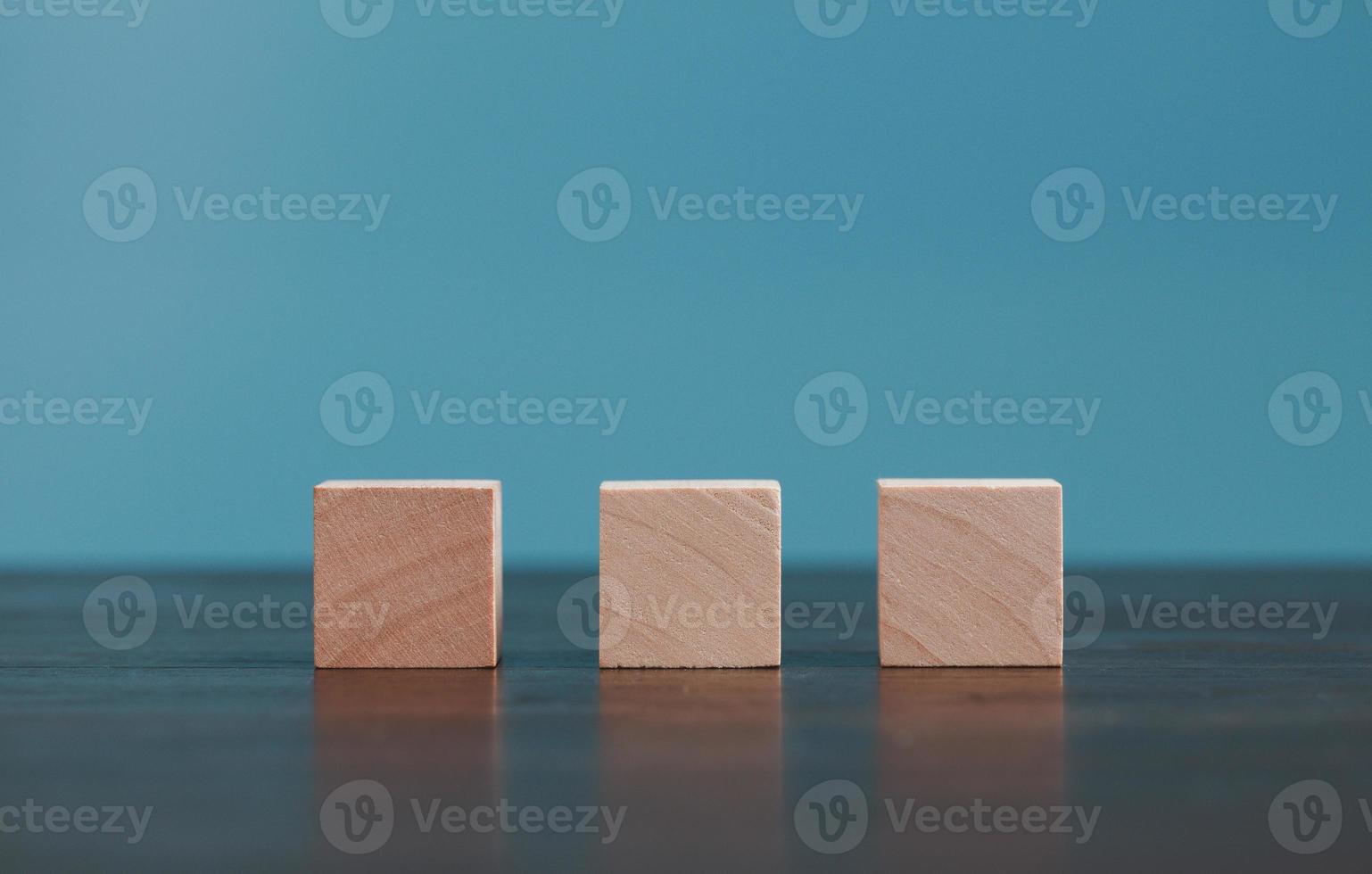 Stacking blank wooden cubes on blue background with copy space for input wording and infographic icon. Empty brown wooden object block for symbol icon put technology, zero gravity, business concept. photo