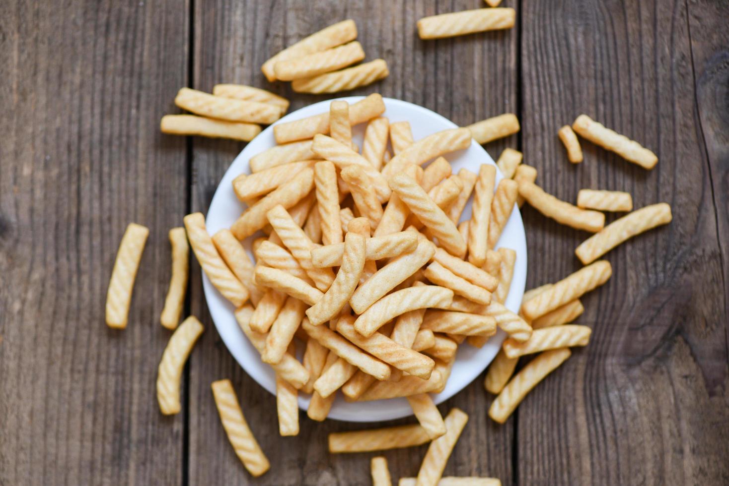 prawn crackers stick on white plate and wooden table background , homemade crunchy prawn crackers or shrimp crisp traditional snack photo