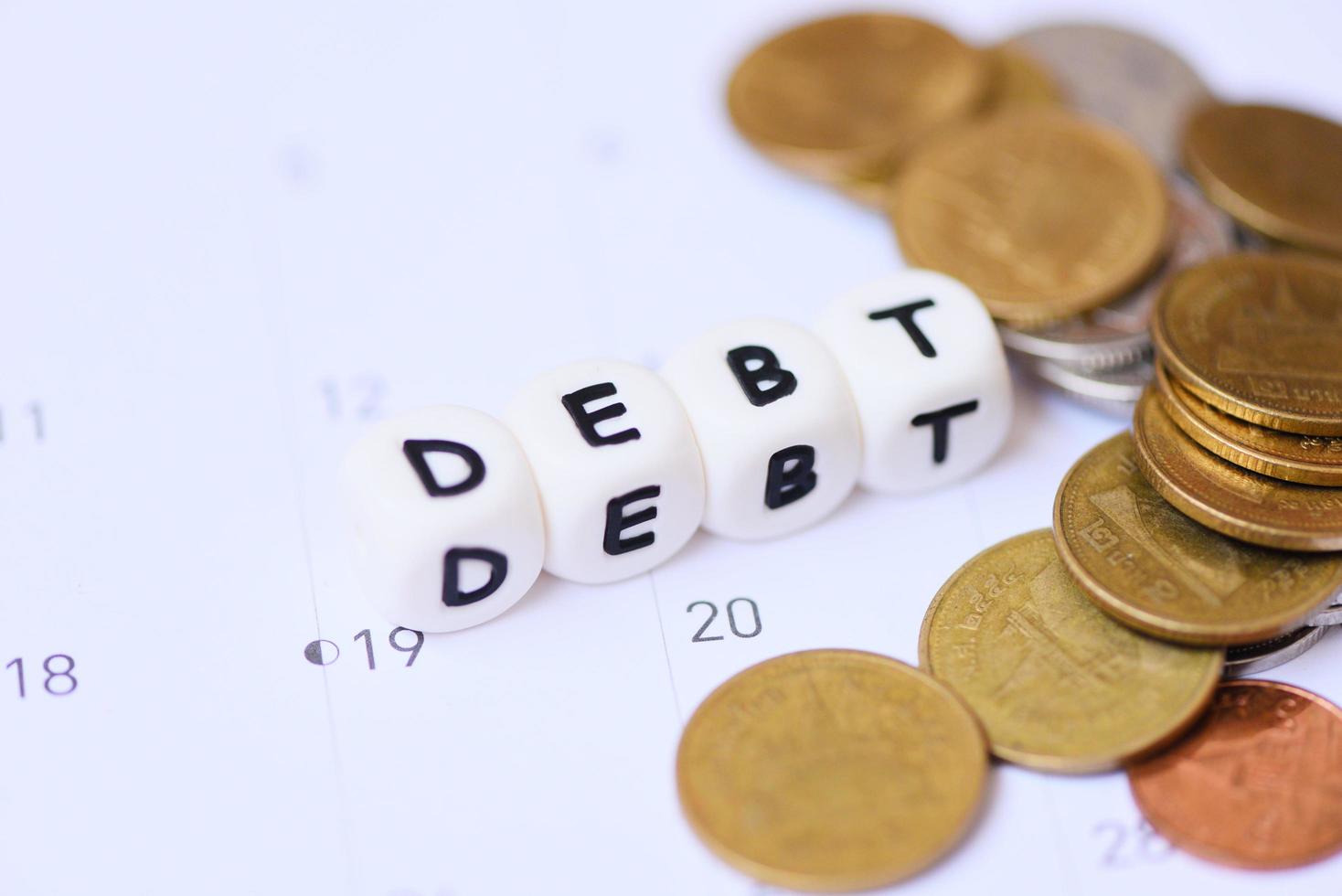 Debt concept with words of debt on calendar and coins background photo