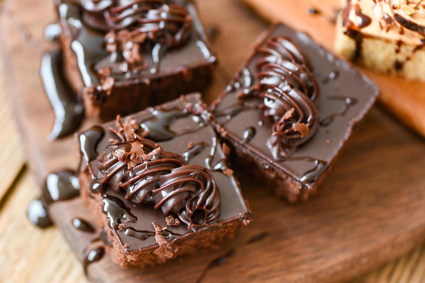 pastel salsa de chocolate delicioso postre servido en la mesa - rebanada de pastel sobre fondo de tablero de corte de madera con chocolate de cobertura foto