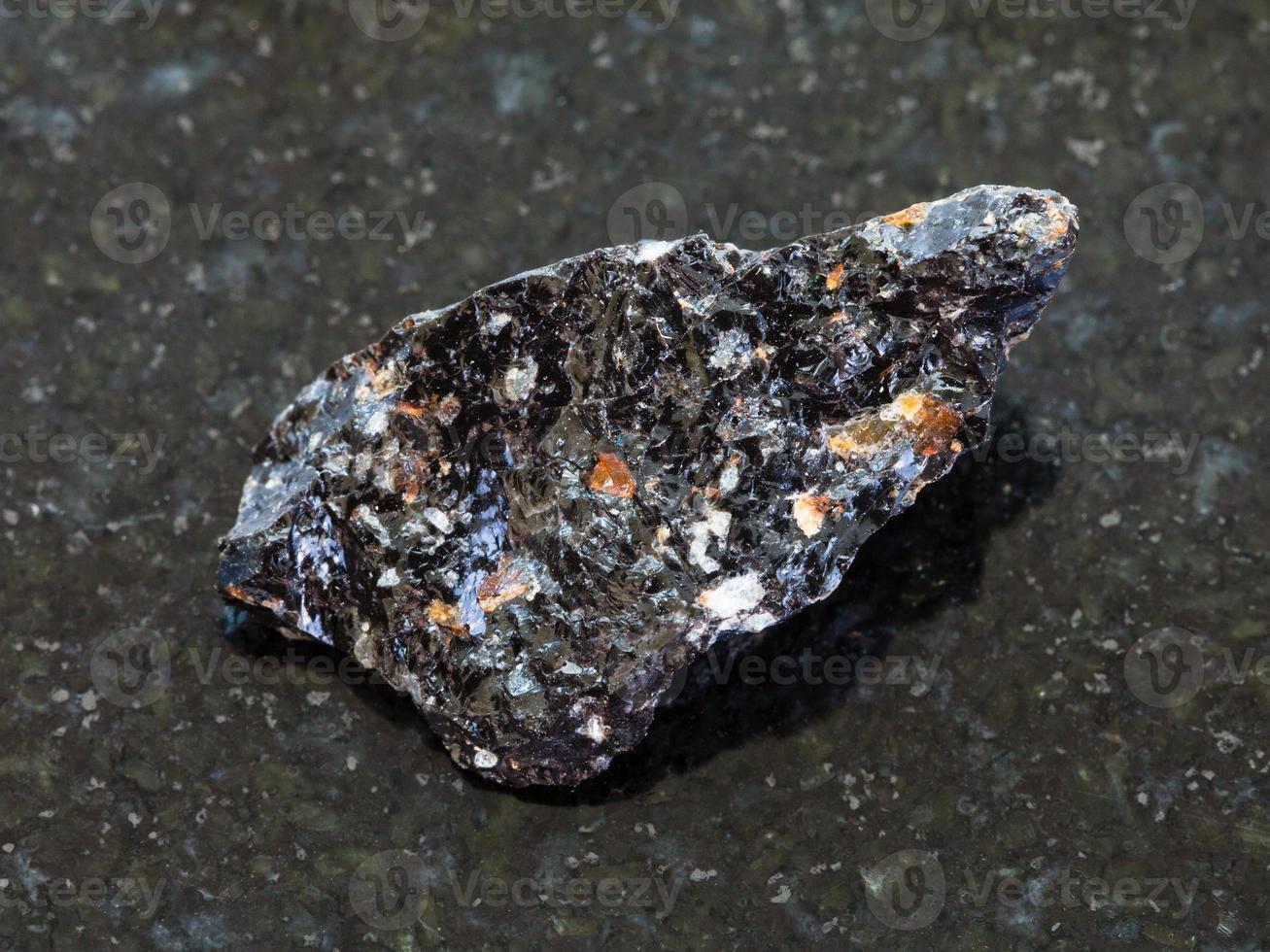 piedra de vidrio volcánico de obsidiana cruda en la oscuridad foto