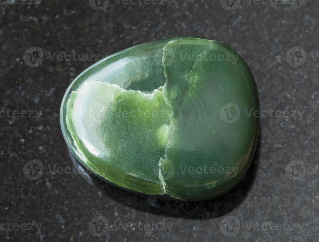 tumbled green nephrite gemstone on dark photo