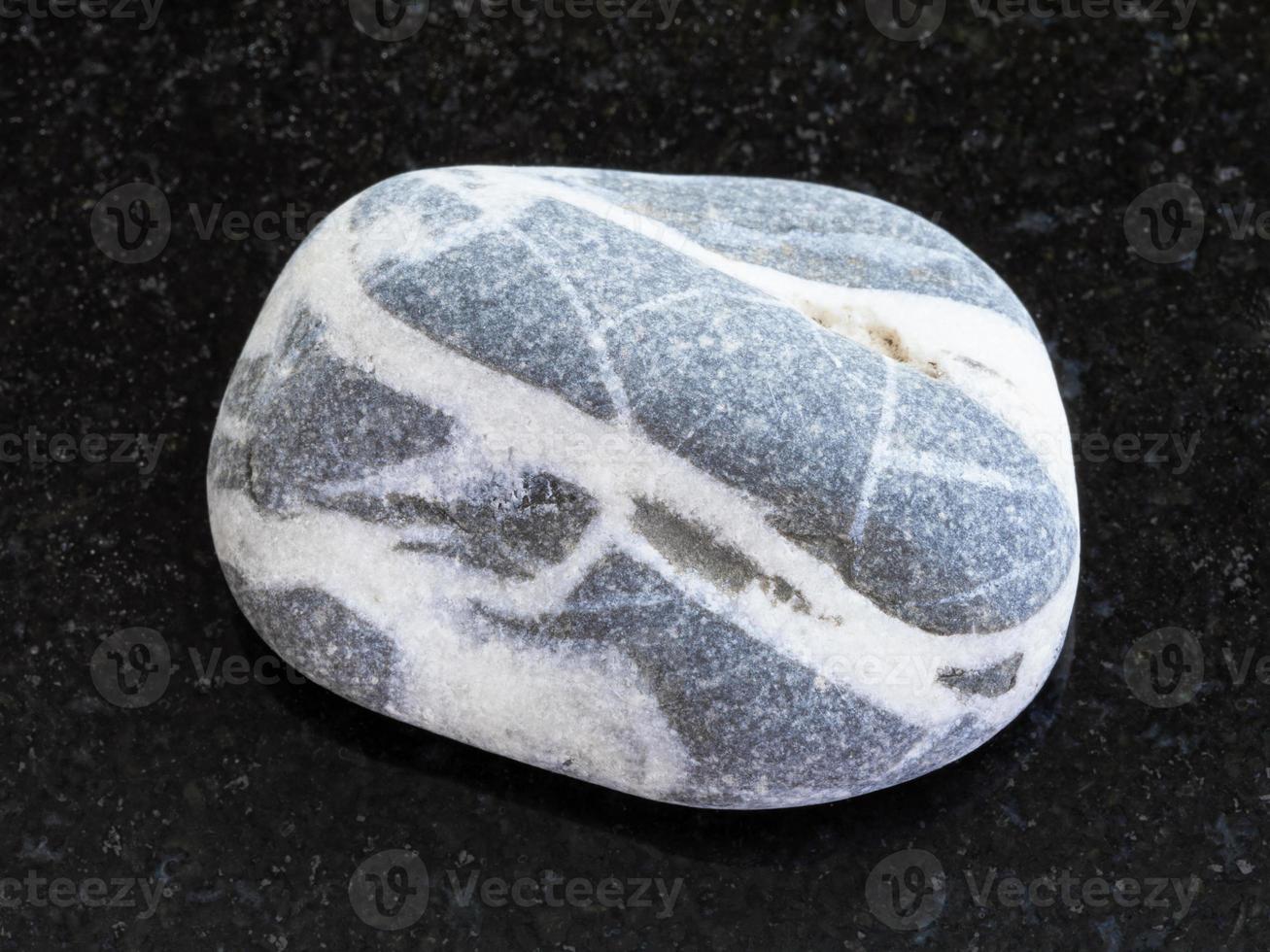 tumbled gray Gneiss stone on dark background photo