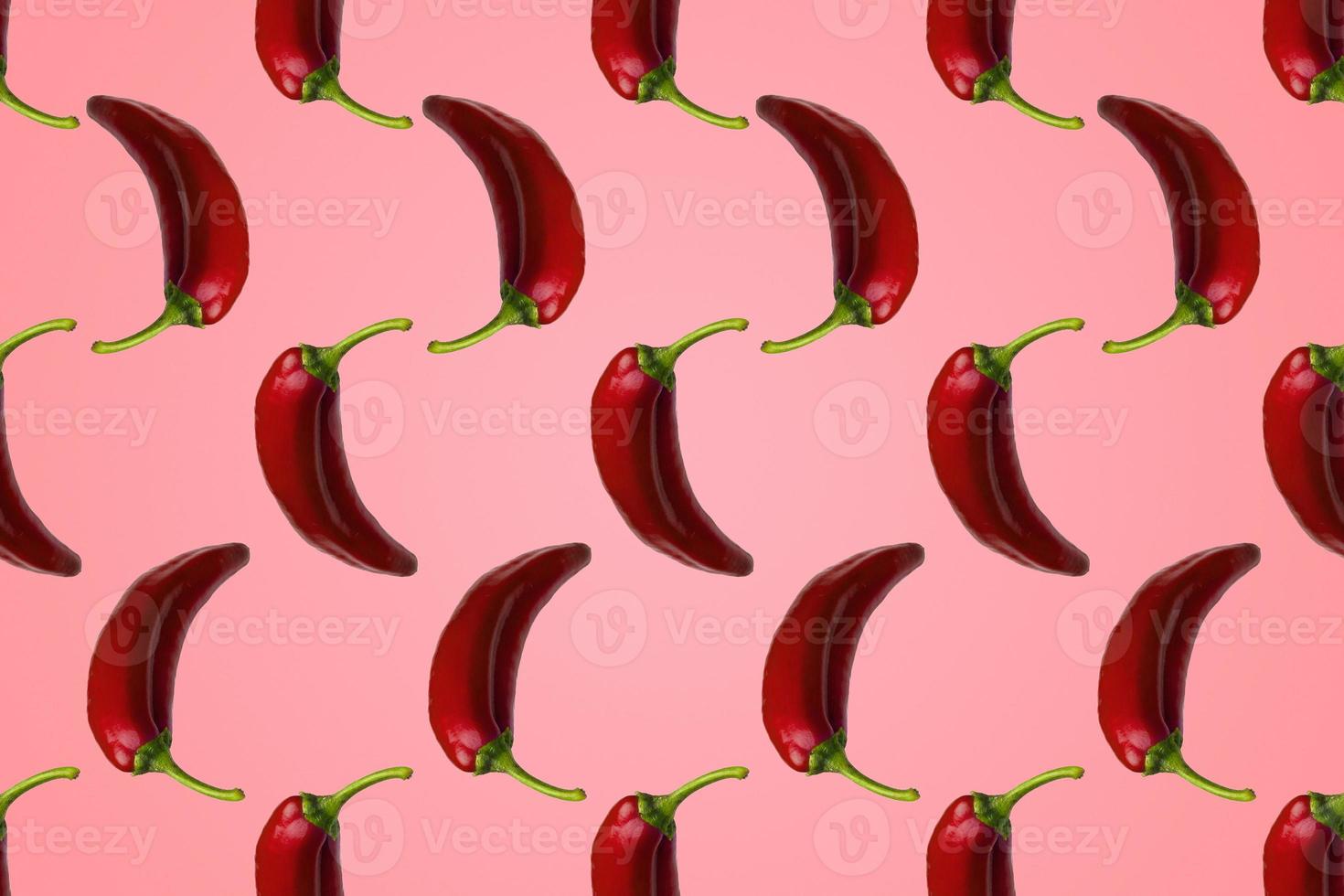 Pattern of red peppers isolated on pink background. Creative photo of peppers aligned with copy space.