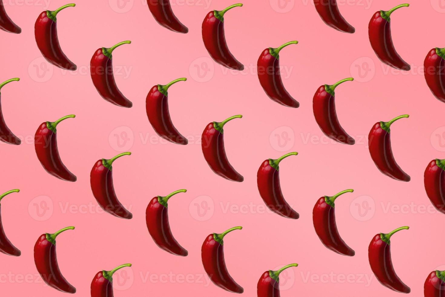 Pattern of red peppers isolated on pink background. Creative photo of peppers aligned with copy space.