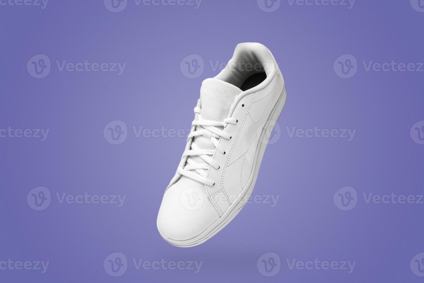 High angle view of white sneaker isolated on purple very peri background. Sportive pair of shoes for mockup. Fashionable stylish sports casual shoes. photo