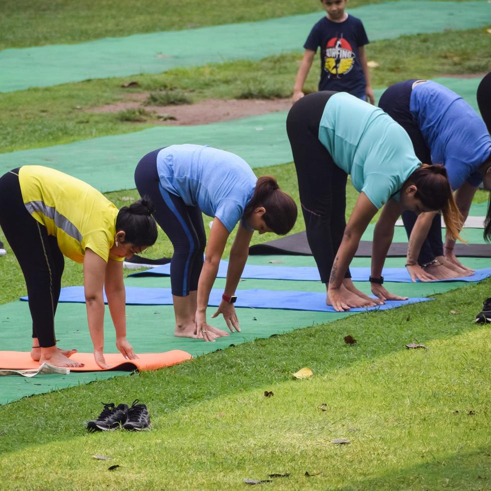 New Delhi, India, June 18 2022 - Group Yoga exercise class Surya Namaskar for people of different age in Lodhi Garden, International Yoga Day, Big group of adults attending a yoga class in park photo