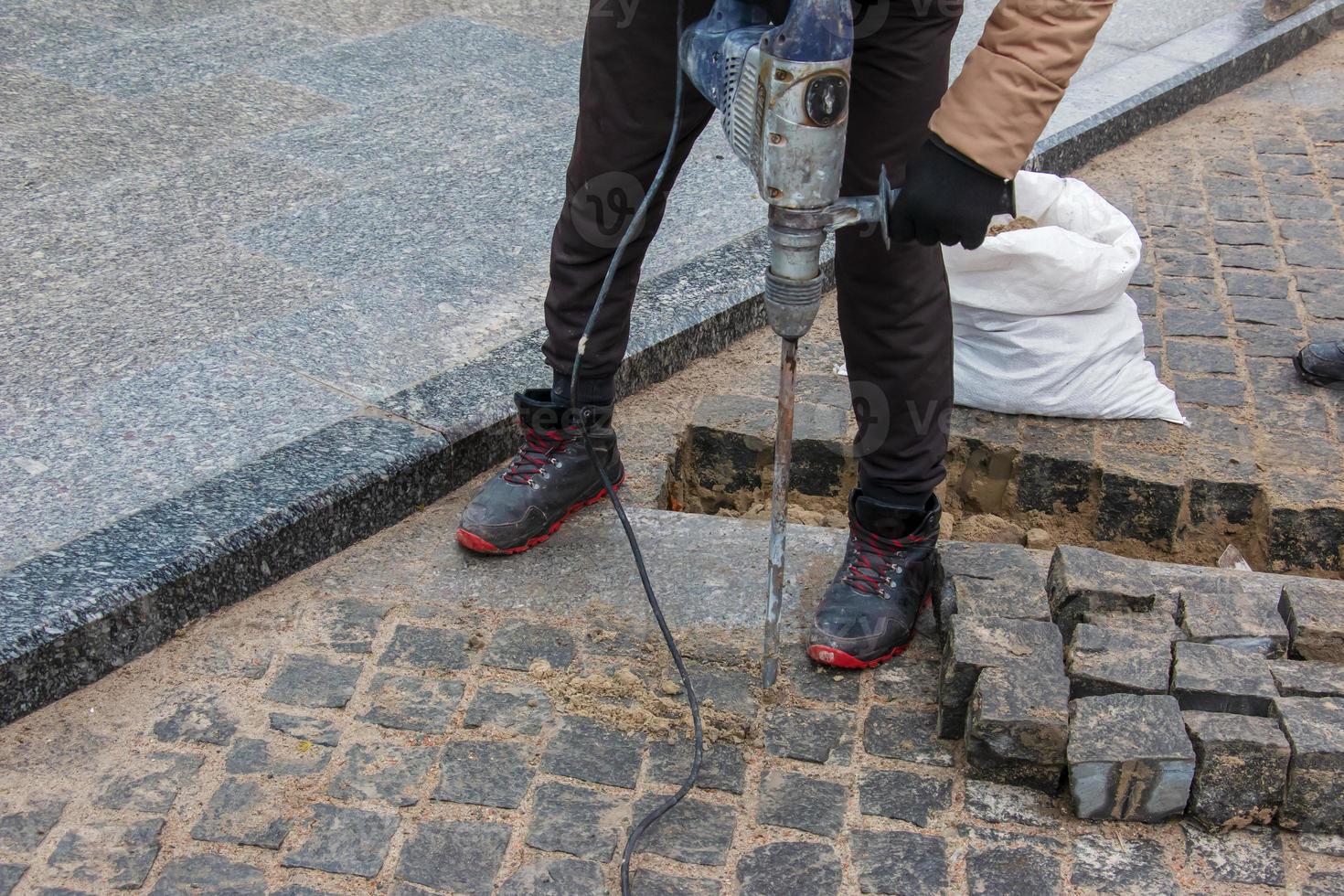 A male worker repairs the pavement with a jackhammer. The work of the municipal service photo