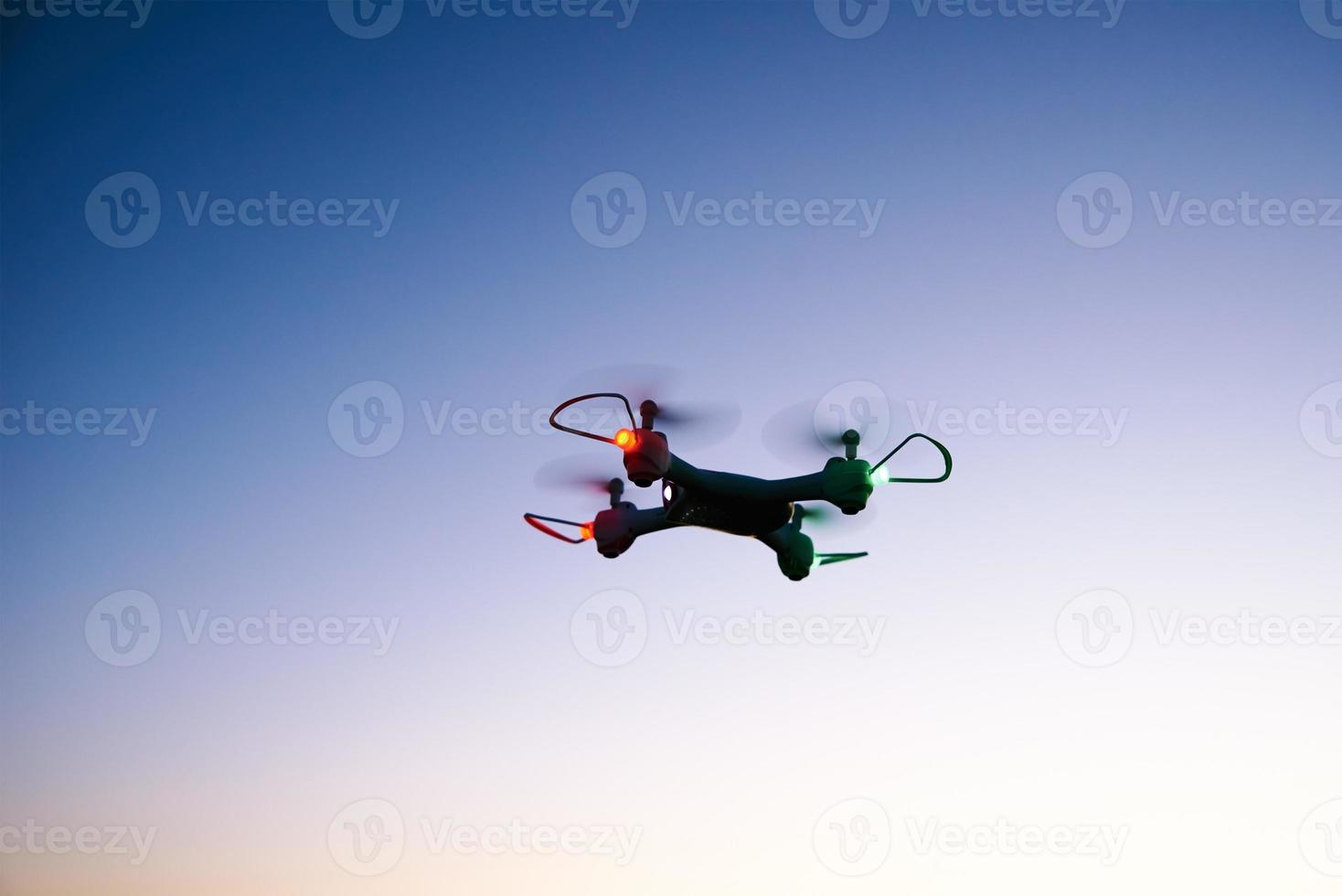 Toy drone quad copter against sunset sky photo