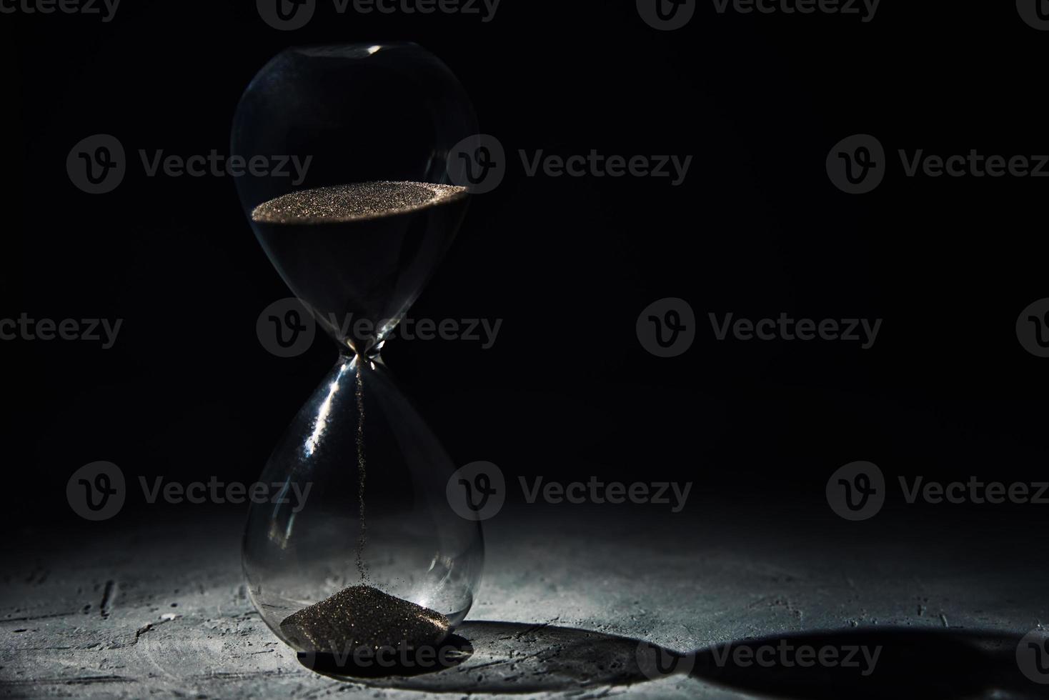 Hourglass on dark background, closeup. Urgency and running out of time concept photo