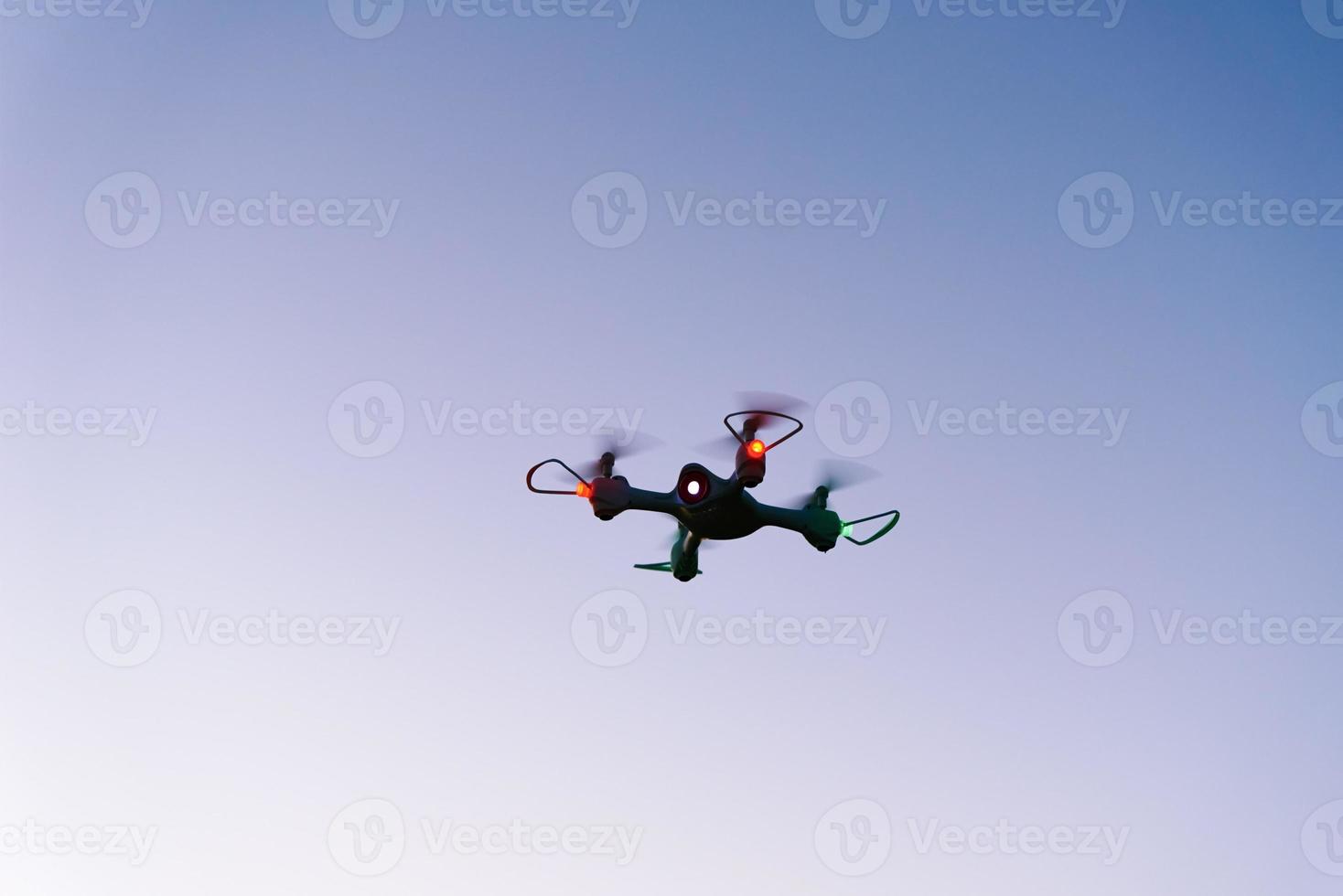 Toy drone quad copter against sunset sky photo