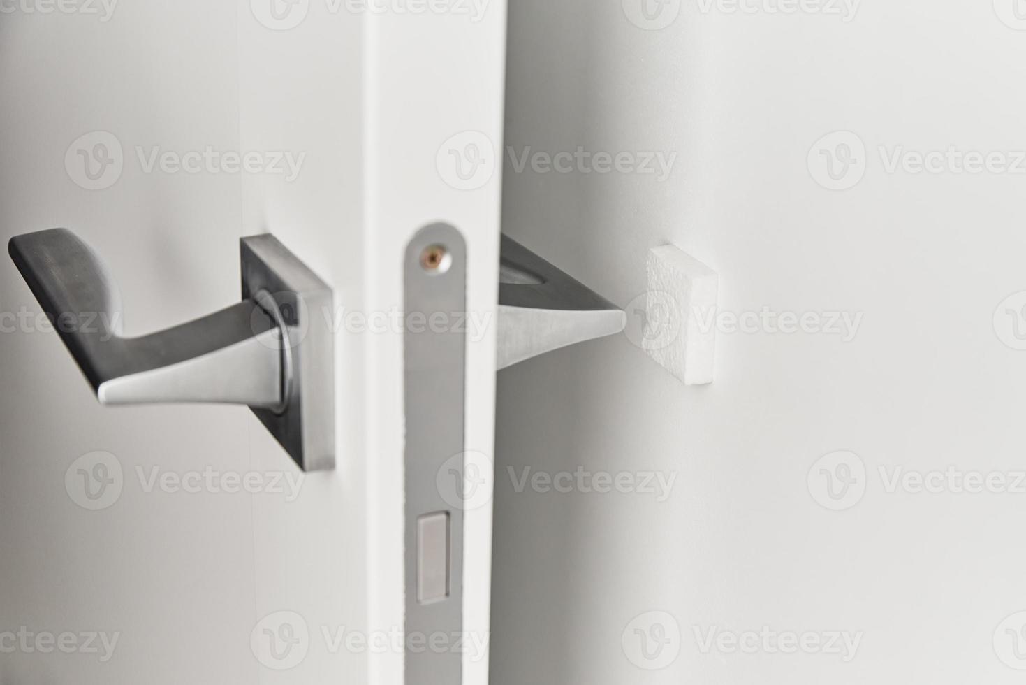 manija de puerta plateada en una puerta blanca. accesorios de muebles, elemento interior. foto