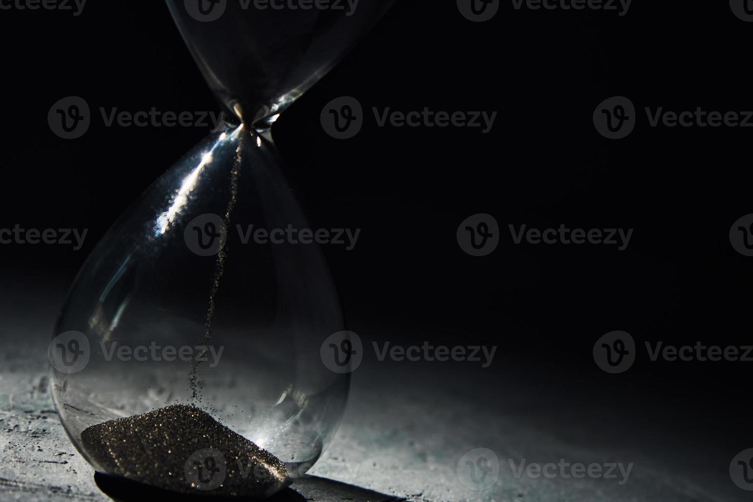 Hourglass on dark background, closeup. Urgency and running out of time concept photo