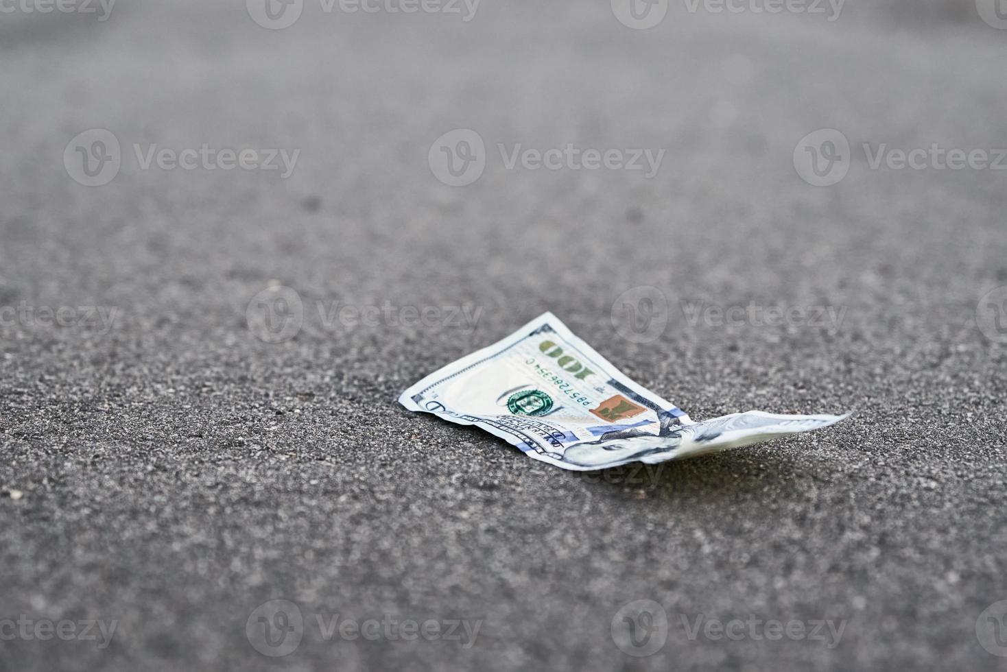 lost money on the road. One hundred dollar bill on pavement photo