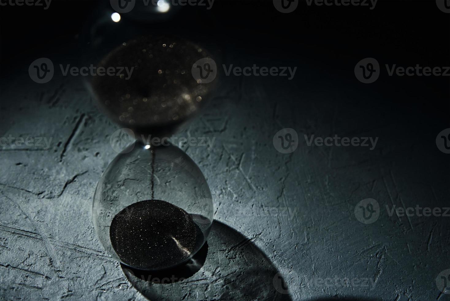 Hourglass on dark background, closeup. Urgency and running out of time concept photo