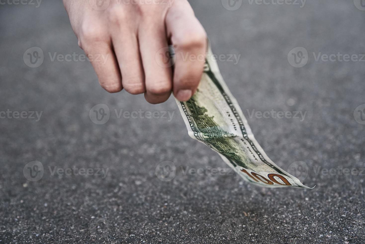 recoger a mano un billete de cien dólares del suelo. concepto de dinero encontrado foto