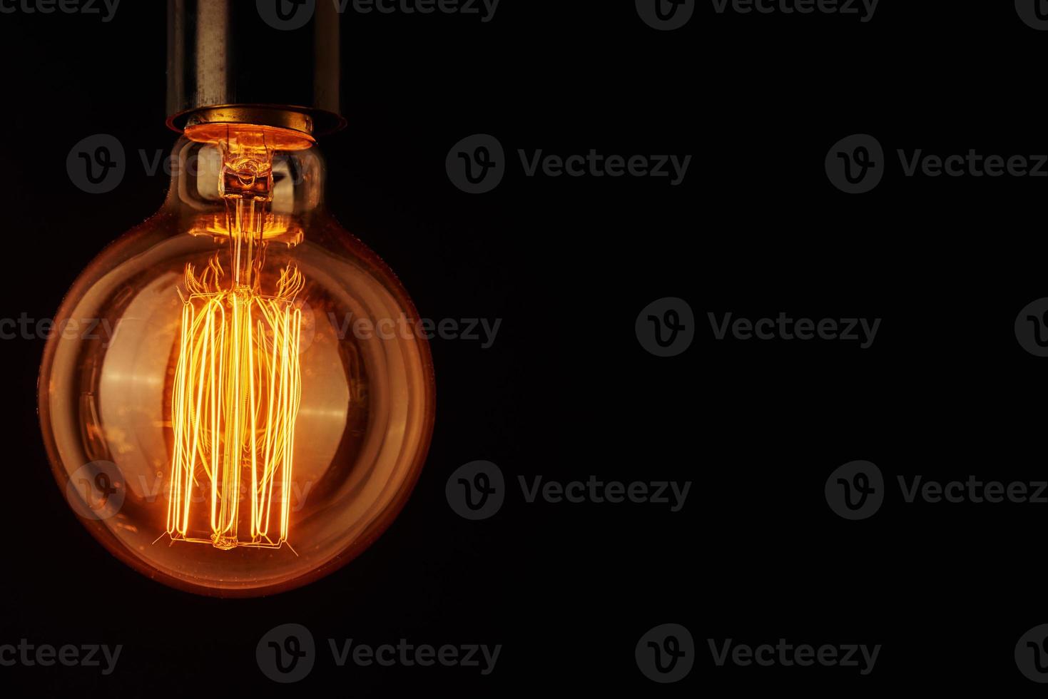 Vintage light bulb on black background, copy space. Glowing edison bulb photo