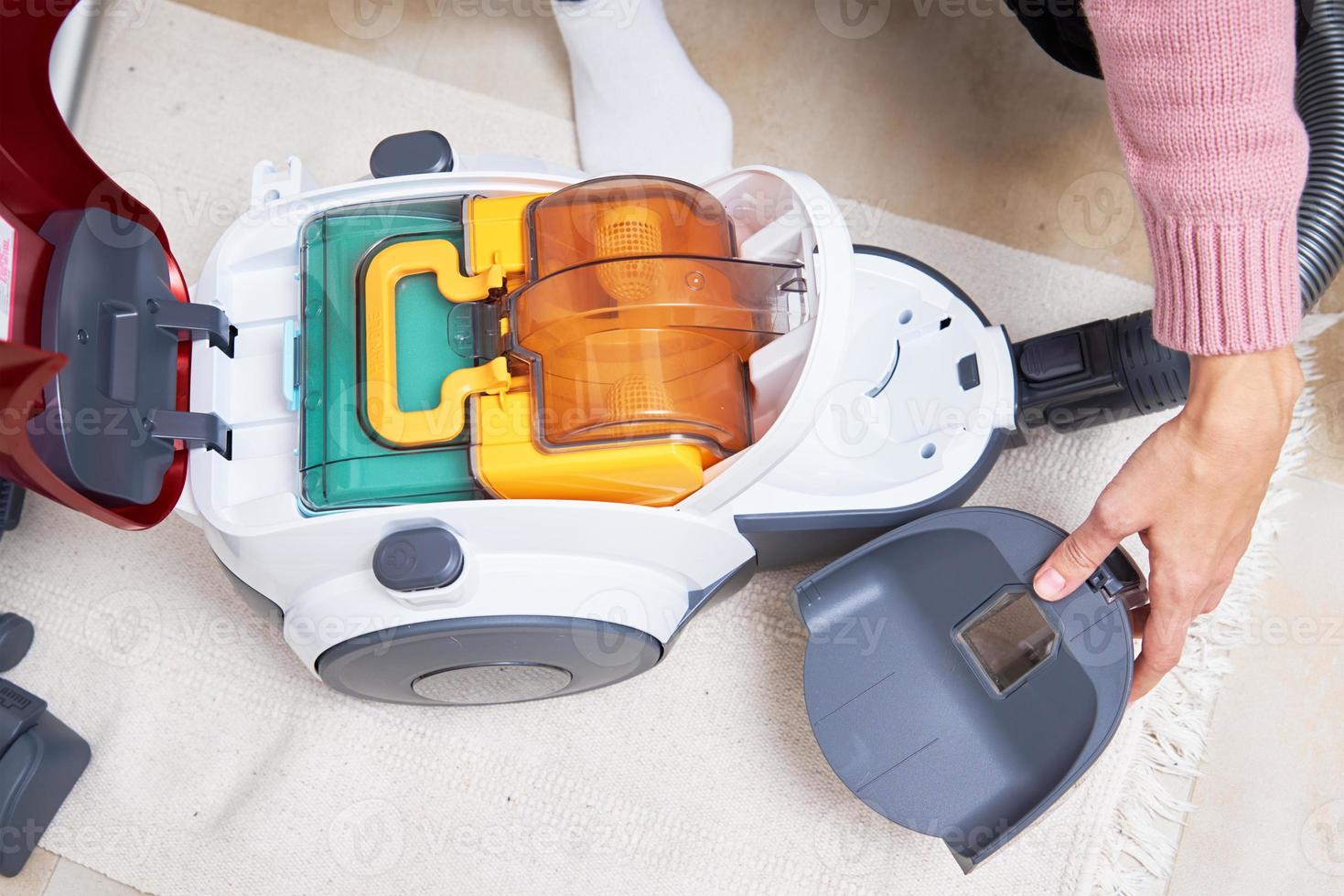 Woman takes out container of dust from vacuum cleaner photo
