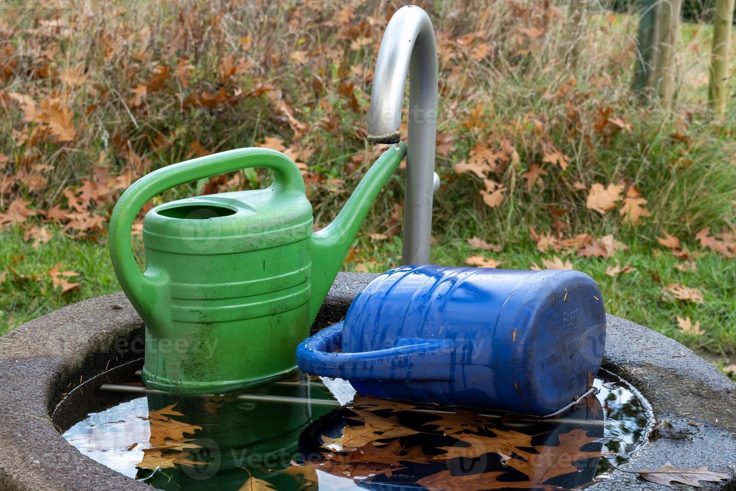 Two watering can in garden photo